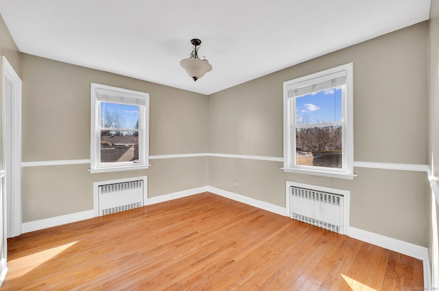 unfurnished dining area with baseboards, wood-type flooring, and radiator