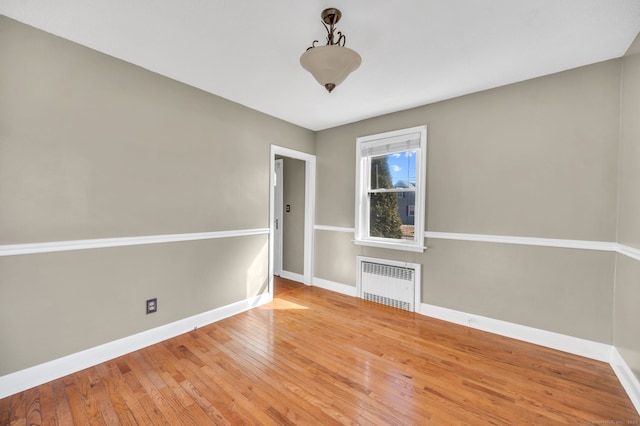 spare room with baseboards, hardwood / wood-style floors, and radiator