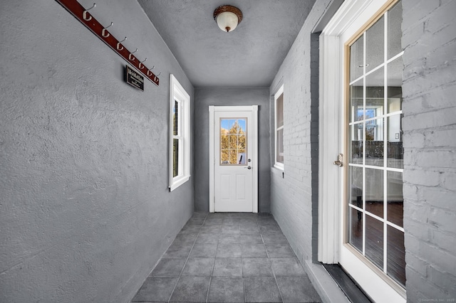 hallway featuring a textured wall and tile patterned flooring