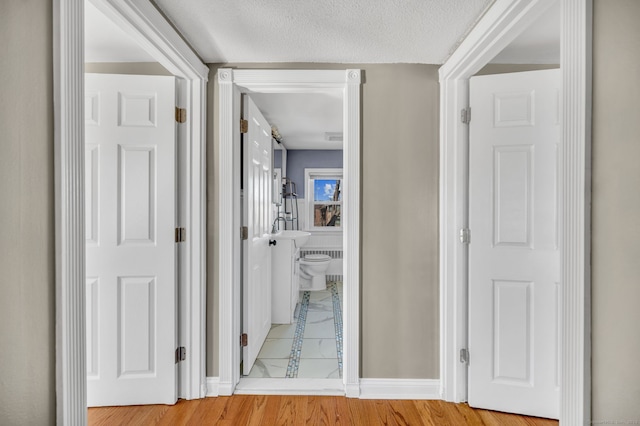 hallway with a textured ceiling and wood finished floors