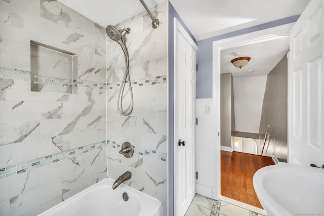 bathroom with a wainscoted wall, marble finish floor, and tub / shower combination