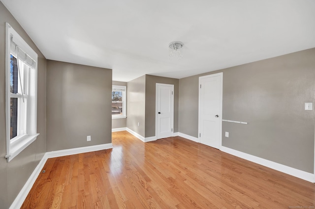 spare room featuring baseboards and light wood-style floors