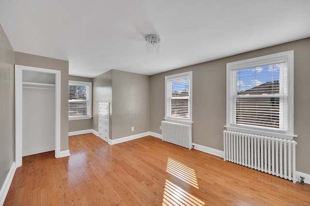 unfurnished bedroom featuring radiator, baseboards, and light wood finished floors