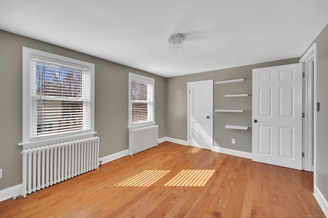 unfurnished bedroom featuring baseboards, light wood finished floors, and radiator