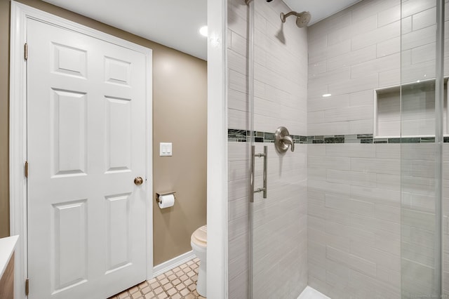 full bathroom with a stall shower, baseboards, and toilet