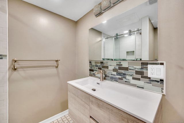 bathroom with visible vents, baseboards, vanity, tiled shower, and decorative backsplash