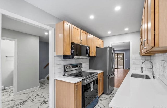 kitchen with marble finish floor, stainless steel appliances, light countertops, a sink, and baseboards