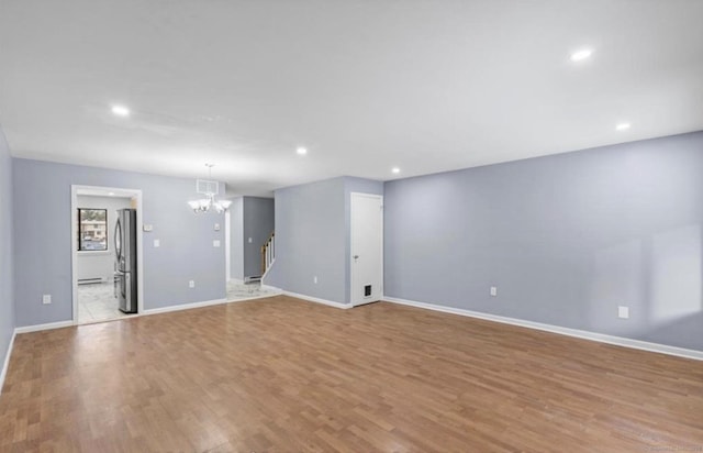 empty room featuring baseboards, visible vents, stairway, wood finished floors, and a chandelier