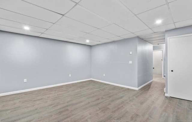 finished below grade area with wood finished floors, a paneled ceiling, and baseboards