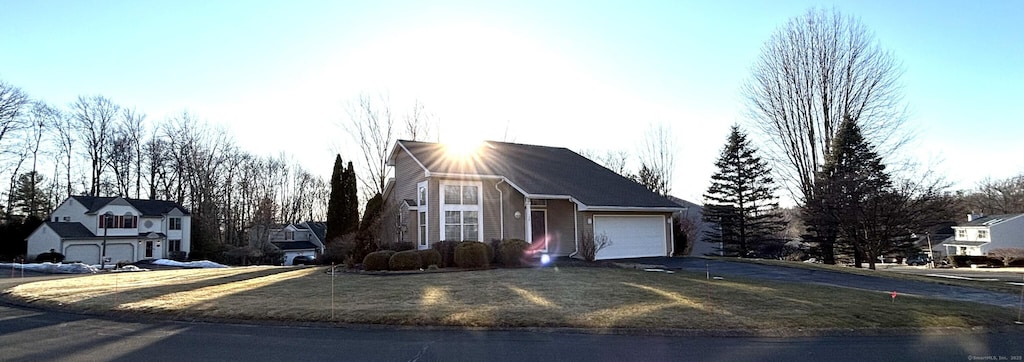 view of front of property featuring aphalt driveway, a front lawn, and a garage