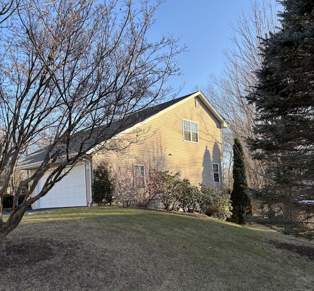 view of side of home featuring a garage, driveway, and a lawn