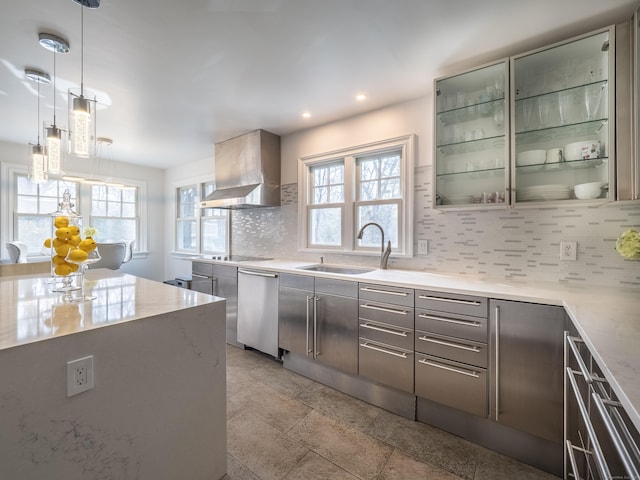 kitchen featuring plenty of natural light, decorative backsplash, a sink, wall chimney range hood, and stainless steel dishwasher