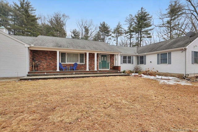 ranch-style house featuring covered porch, brick siding, and a front lawn