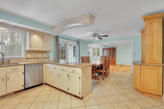 kitchen with dishwasher, a peninsula, light tile patterned flooring, and a sink