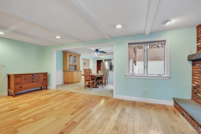 living room featuring visible vents, beamed ceiling, light wood-style flooring, and baseboards