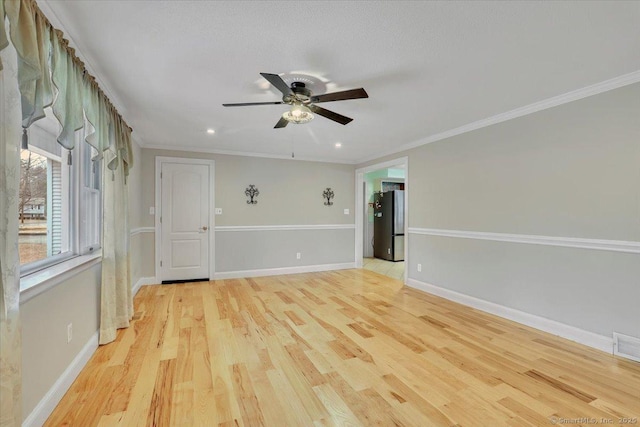 empty room featuring ornamental molding, light wood-type flooring, and baseboards