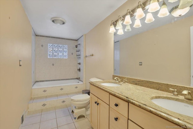 bathroom featuring toilet, tile patterned flooring, tiled shower / bath, and a sink