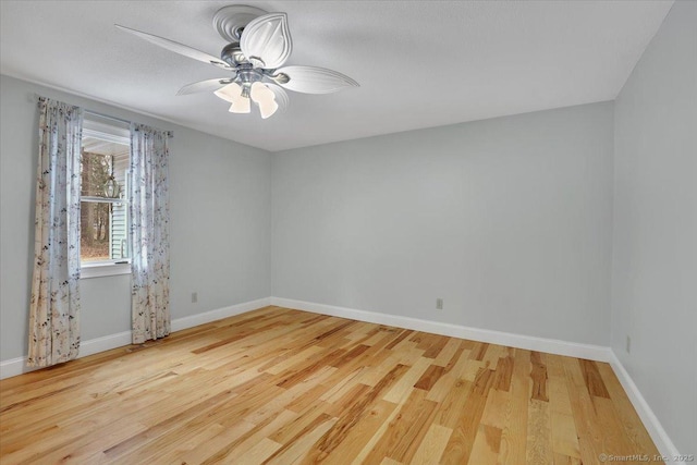 spare room with a ceiling fan, baseboards, and wood finished floors