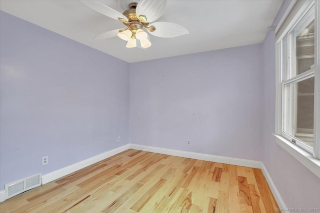 spare room featuring a ceiling fan, visible vents, baseboards, and wood finished floors