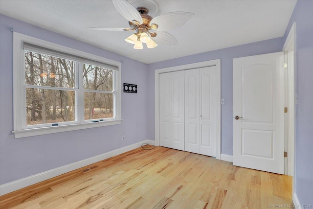 unfurnished bedroom featuring a ceiling fan, visible vents, baseboards, a closet, and light wood-type flooring