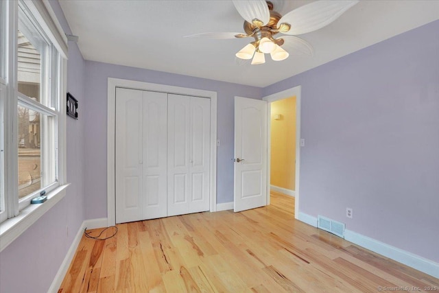 unfurnished bedroom featuring light wood-style flooring, a closet, visible vents, and baseboards