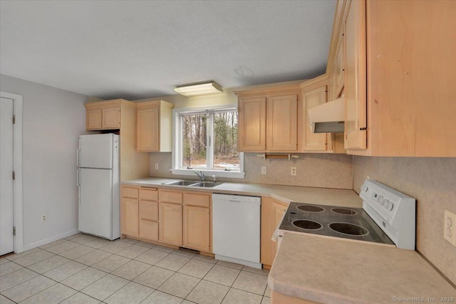 kitchen with white appliances, light countertops, under cabinet range hood, light brown cabinets, and a sink