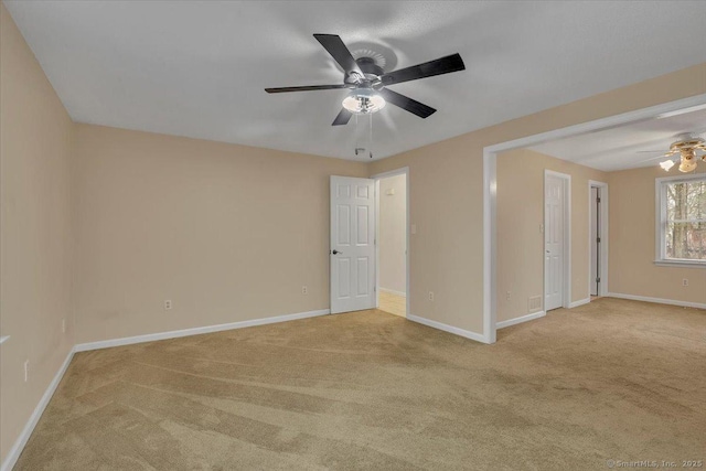 empty room with baseboards, a ceiling fan, and light colored carpet