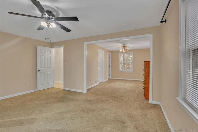 spare room featuring light carpet, baseboards, and a ceiling fan