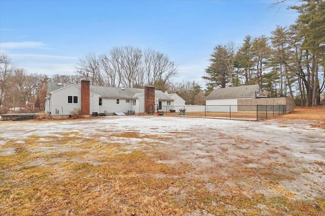 rear view of property with a chimney and fence