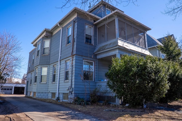 view of home's exterior with a sunroom and an outdoor structure