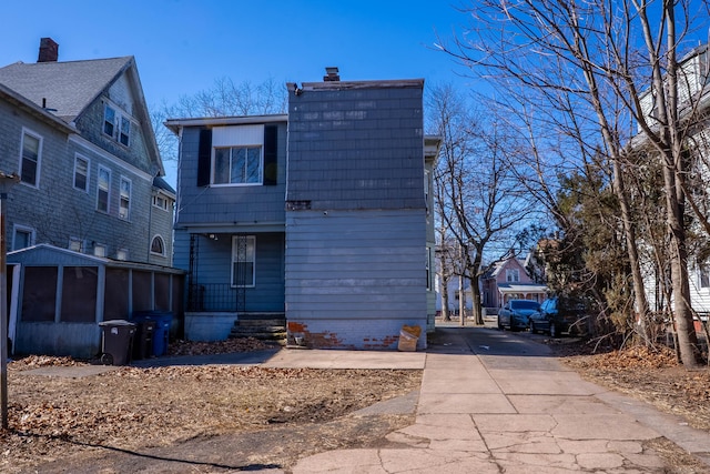 back of property with driveway and a chimney