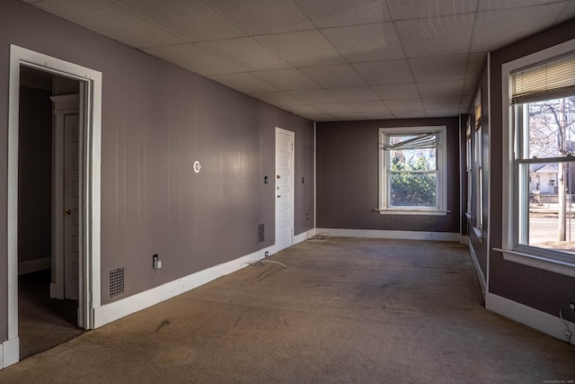 unfurnished room with a paneled ceiling, baseboards, visible vents, and carpet