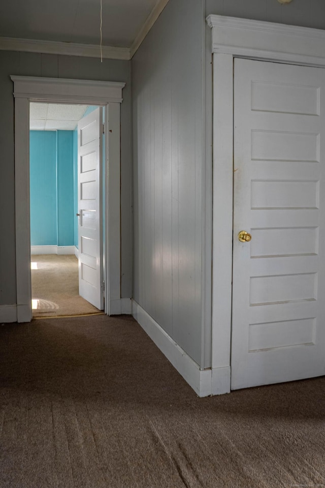 hallway featuring baseboards, ornamental molding, and carpet flooring