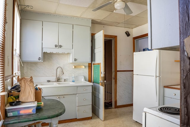 kitchen featuring a drop ceiling, white appliances, a sink, a ceiling fan, and light floors