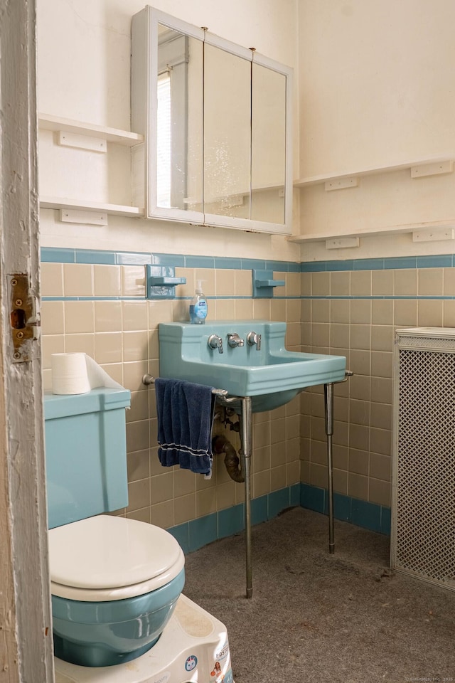 half bath featuring wainscoting, toilet, and tile walls