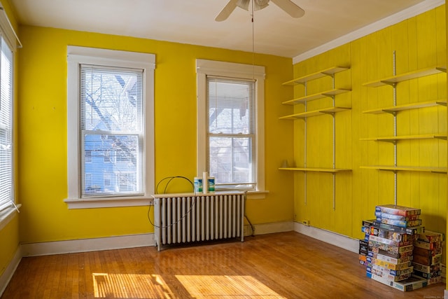 empty room with radiator, plenty of natural light, baseboards, and wood finished floors