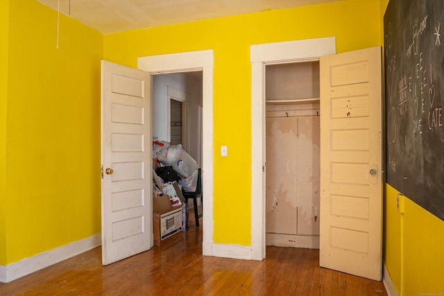 unfurnished bedroom featuring a closet, hardwood / wood-style flooring, and baseboards