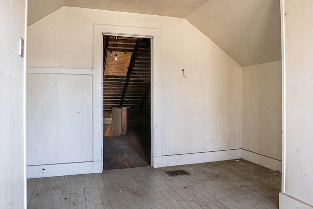 additional living space featuring vaulted ceiling, visible vents, and hardwood / wood-style flooring