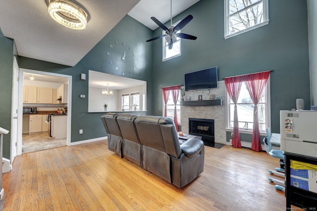 living room with a wealth of natural light, a fireplace with flush hearth, light wood-style flooring, and baseboards