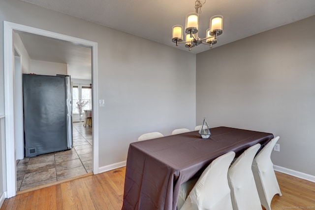 dining space featuring baseboards, an inviting chandelier, visible vents, and light wood-style floors