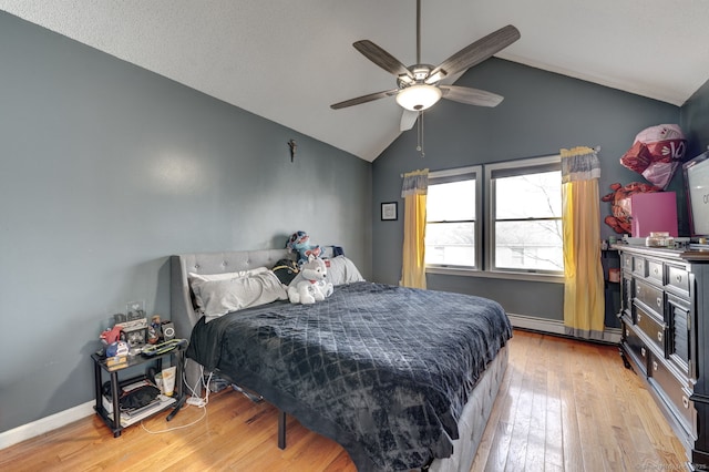 bedroom featuring ceiling fan, a baseboard heating unit, baseboards, vaulted ceiling, and light wood finished floors