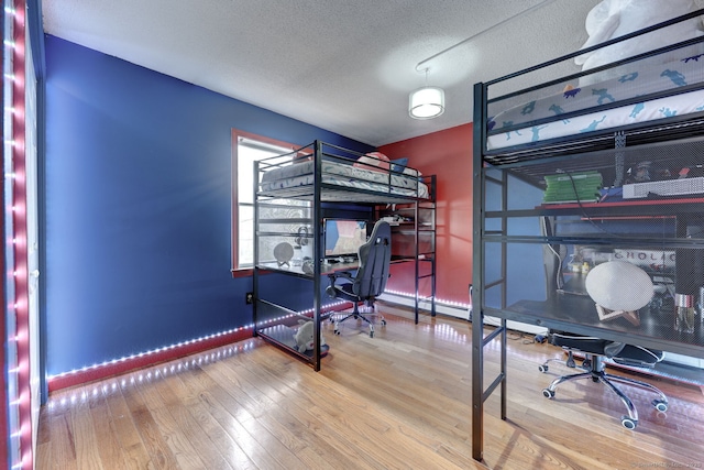 bedroom featuring a textured ceiling, baseboards, and wood finished floors