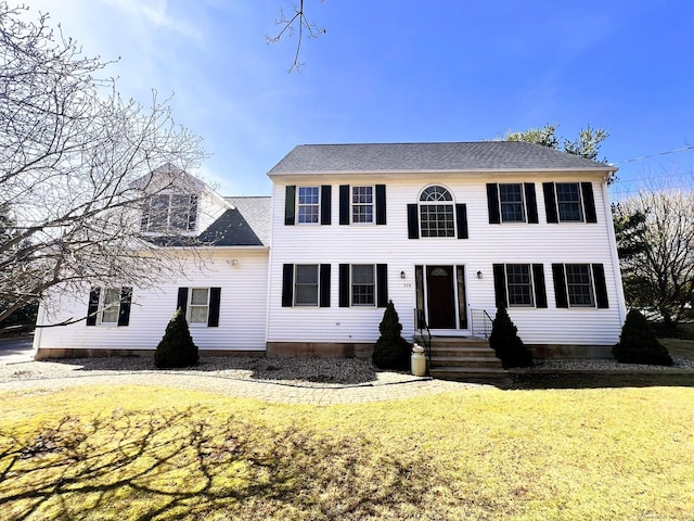 colonial house with entry steps, a front lawn, and roof with shingles