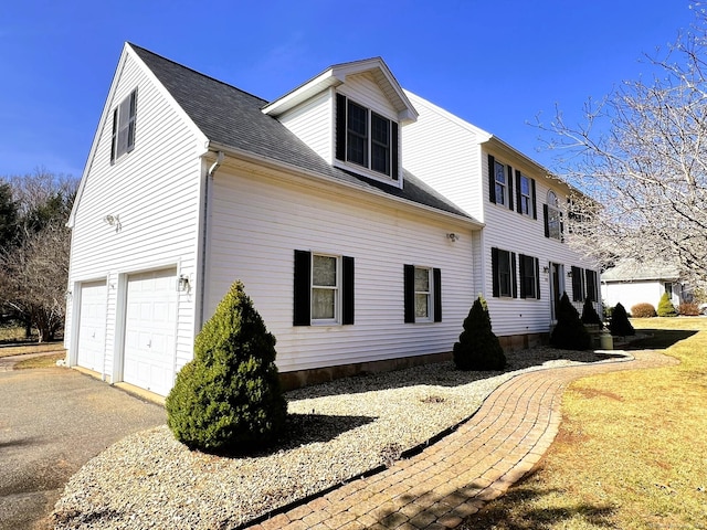 back of house with aphalt driveway, a shingled roof, and a garage