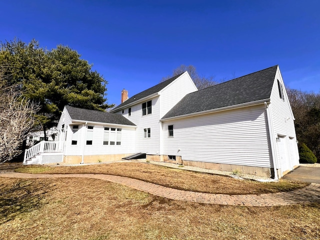 rear view of house featuring a garage and a shingled roof