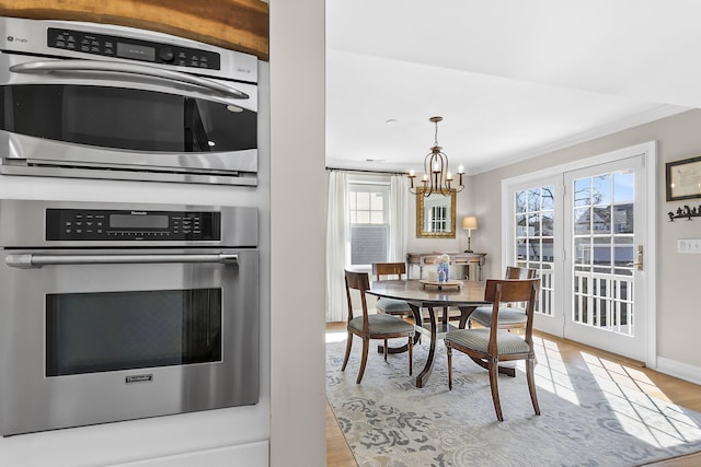 dining area featuring a chandelier, baseboards, light wood-style flooring, and crown molding