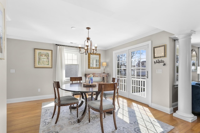 dining area featuring ornamental molding, light wood-type flooring, and decorative columns