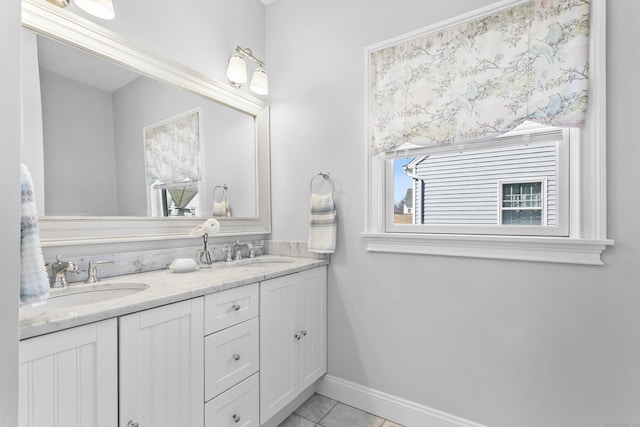 full bath featuring double vanity, baseboards, a sink, and tile patterned floors