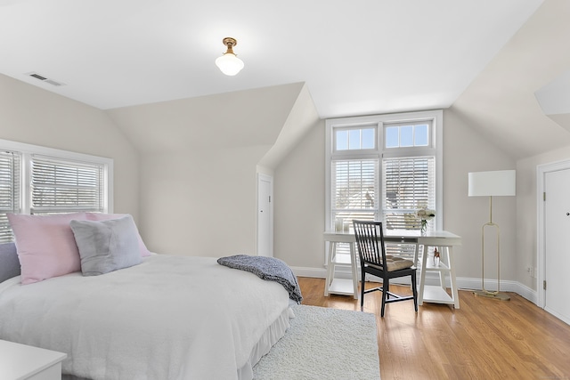 bedroom with visible vents, vaulted ceiling, light wood-style flooring, and baseboards