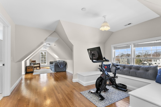 workout area with light wood-type flooring, baseboards, visible vents, and vaulted ceiling